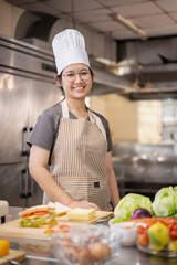 Young woman learning to cook, sandwiches and fresh vegetables placed on the table in a modern kitchen.