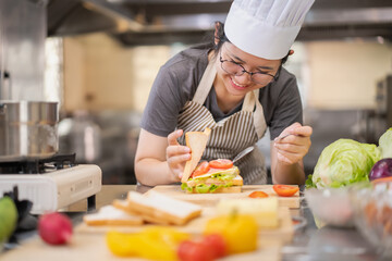 Young woman learning to cook, sandwiches and fresh vegetables placed on the table in a modern...