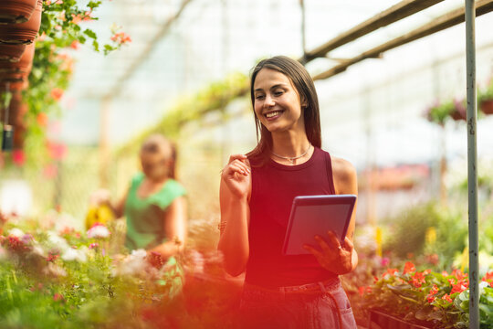 Woman Using Tablet In A Colorful Greenhouse - Powered by Adobe