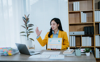 Young beautiful asian businesswoman using calculator while working with financial data and laptop...