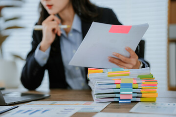 Smiling Asian accountant working with calculator and analyzing financial documents. and working on...