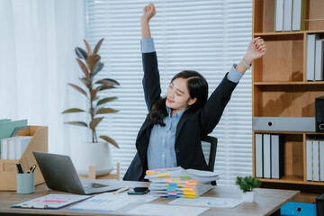 Young asian woman relaxes at office desk with laptop. Enjoying break moment, resting after work...