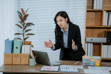 Smiling Young asian accountant business woman working with documents using calculator and laptop...