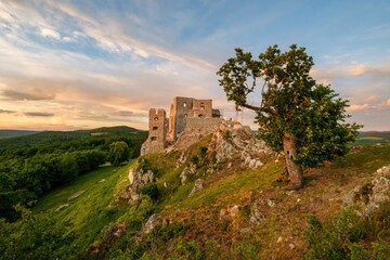 Medieval building illuminated by the setting sun and blue sky with clouds. Ruins of Hrusov Castle,...