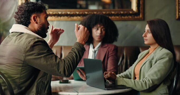 Discussion, laptop and business people in coffee shop for planning creative project with publishing. Computer, collaboration and editors with author for meeting on proofreading in restaurant cafe.