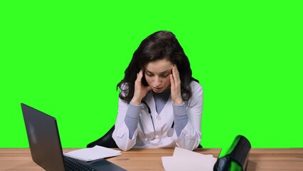 Female doctor feeling tired, sitting at desk with laptop on the chroma key
