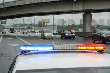 A police car's light panel is on with a highway in the background.