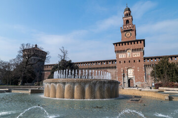 The iconic Torre del Filarete at Sforza Castle in Milan, Italy, captured under the sunlight. The fortress-like structure showcases Renaissance architecture with brick masonry, arched windows, and defe