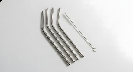 Several stainless steel straws and a cleaning brush are arranged on a white surface.