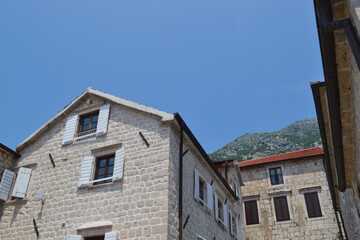 Historic Stone Buildings of Perast with Traditional Shutters and Mountain Backdrop under Clear Sky