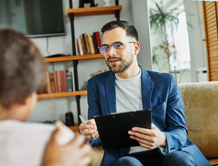 Portrait of a man psychologist talking to patient in his office in clinic. Giving support to a...