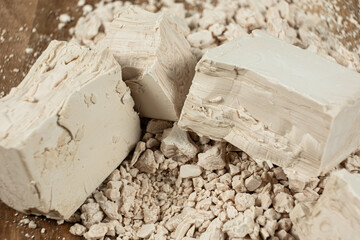Compressed fresh yeast cubes close-up on a wooden background.