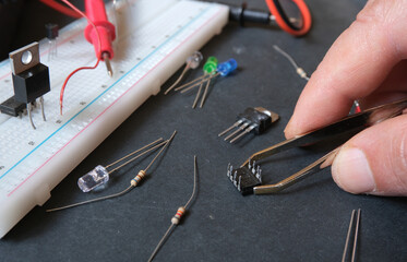 Electronics construction in laboratory. Hands connecting wires to breadboard. The engineer,...