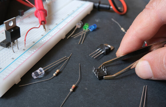 Electronics construction in laboratory. Hands connecting wires to breadboard. The engineer, installing the prototype robot's electronic module.