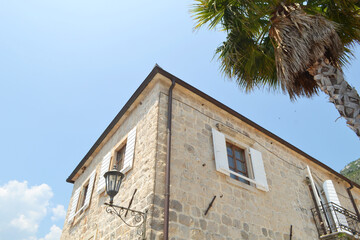 Historic Stone Buildings of Perast with Traditional Shutters and Mountain Backdrop under Clear Sky