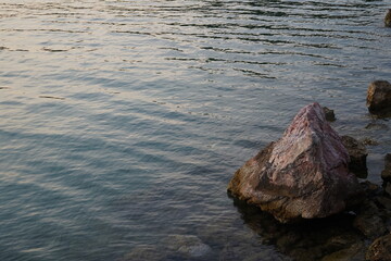 Rippling waves reflect soft hues at dusk by the tranquil shoreline, inviting contemplation and...