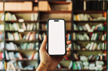 Smartphone with blank white screen mockup held in hand, with a blurred library background. Perfect...