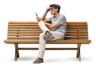 Mature man in his 50s sitting on a wooden bench and using a smartphone, studio shot isolated on...