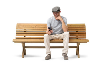 Smiling mature man in his 50s sitting on a wooden bench and using a smartphone. Studio shot,...