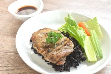 grilled slice chicken on black riceberry with cucumber carrot and lettuce on plate dipping Thai...