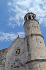 Close-up of Historic Stone Bell Tower and Church Facade in Perast, Montenegro, under Blue Sky