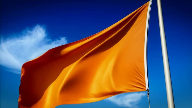 Bright orange warning flag waving against vivid blue sky, potential hazard advisory and caution, coastal safety banner on pole, clear day outdoors
