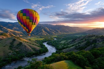 Fototapeta premium Colorful hot air balloon gliding over lush valleys during sunset in mountainous landscape