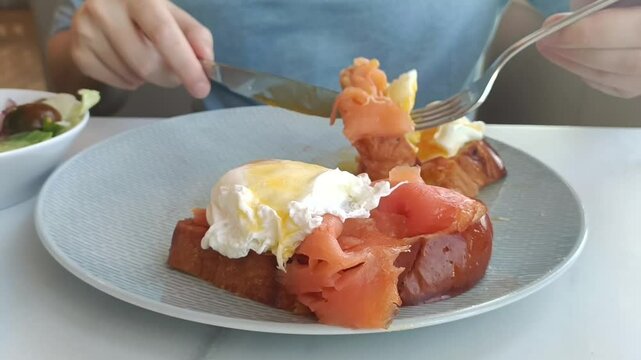 Crop close-up portrait of a man eats Benedict eggs and toasts on cafe