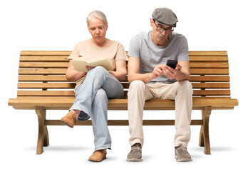 Mature couple sitting together on a wooden bench, woman reading a book and man using a smartphone....