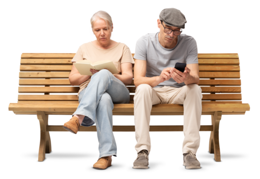 Mature couple sitting together on a wooden bench, woman reading a book and man using a smartphone. Studio image isolated on white background. Casual outfits, man wearing reading glasses and a hat