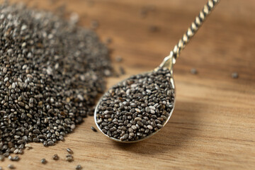Chia seeds in a spoon on a wooden background, close-up.
