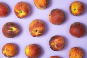 Fruity summer background whole peaches on purple background top view.