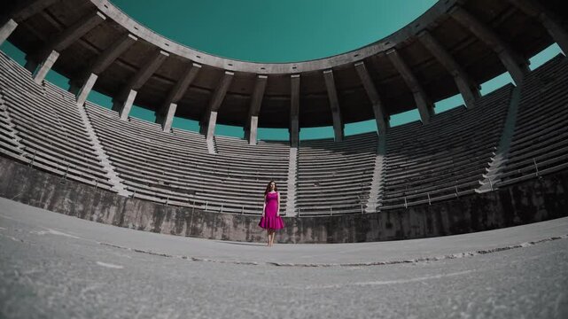 Femme en robe fuchsia dans un stade vide au ciel turquoise