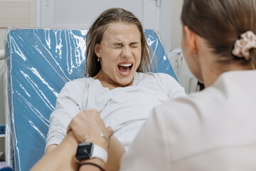 Young woman in labor and contractions in a delivery room on a gynecological chair. Concept of...