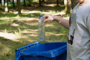 children clean up the forest by throwing empty bottles into a bag and a trash can