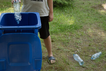 children clean up the forest by throwing empty bottles into a bag and a trash can