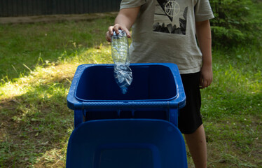 children clean up the forest by throwing empty bottles into a bag and a trash can