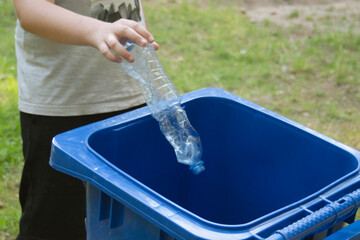 children clean up the forest by throwing empty bottles into a bag and a trash can