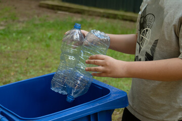 children clean up the forest by throwing empty bottles into a bag and a trash can