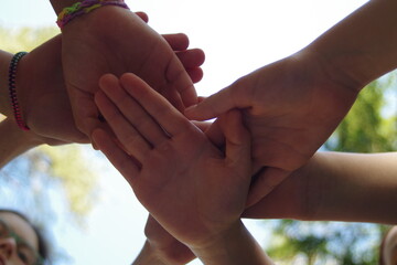 they hold their hands together symbolizing friendship, unity, and peace. , against the sky