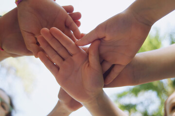 they hold their hands together symbolizing friendship, unity, and peace. , against the sky