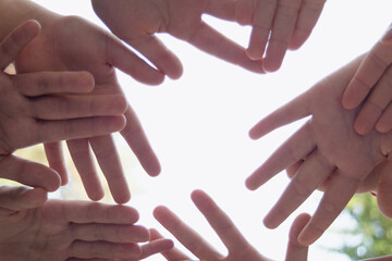 they hold their hands together symbolizing friendship, unity, and peace. , against the sky