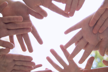 they hold their hands together symbolizing friendship, unity, and peace. , against the sky