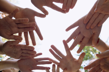 they hold their hands together symbolizing friendship, unity, and peace. , against the sky