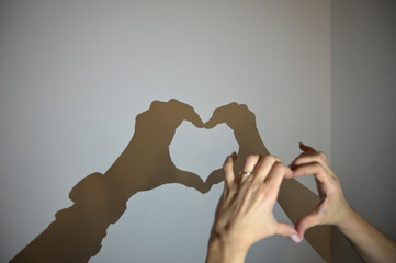 mani che formano un cuore con le ombre sul muro