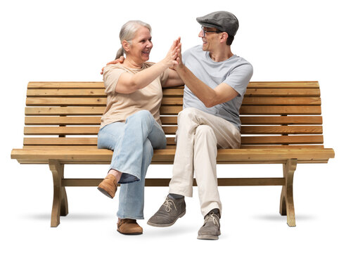 Happy mature couple sitting on a wooden bench, embracing and smiling with joy. A cheerful and affectionate moment together. Studio shot isolated on white background. Both are casually dressed.