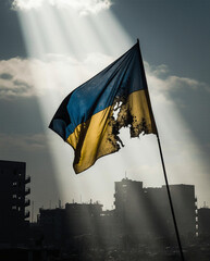A tattered Ukrainian flag (blue and yellow) waving in the wind amidst a war-torn urban landscape. The flag is partially burned, with visible bullet holes, symbolizing resistance. The background shows 