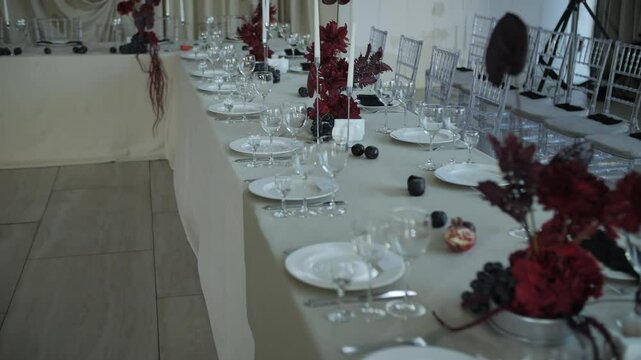 Long wedding table with elegant red floral centerpiece and glassware