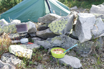 Tourist camp in the mountains. Tourist place with a tent and a field kitchen. Prepared food against the background of the tent.