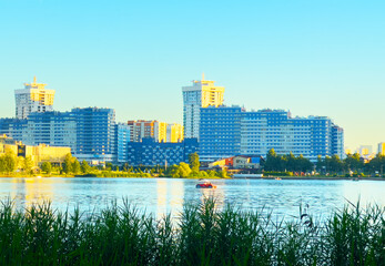 City near lake at sunset. Downtown Minsk and Lake Drozdy. Long Panoramic River Downtown City Skyline. Panarama of City with buildings and  houses on waterfront. buildings and downtown city skyline